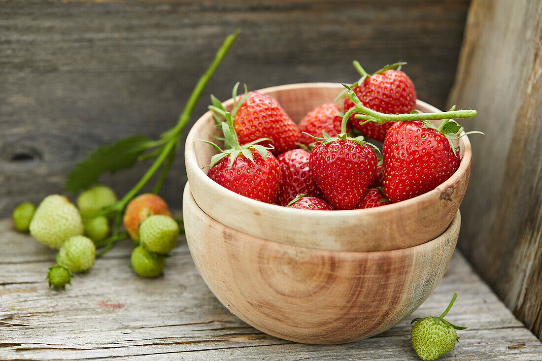 Freshly picked strawberries in a wooden bowl, standing in a wooden box