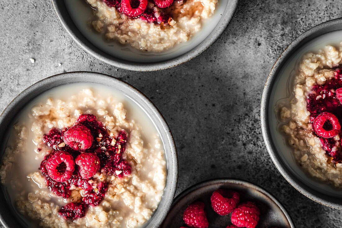 Breakfast Oatmeal and raspberry porridge bowls on grey surface