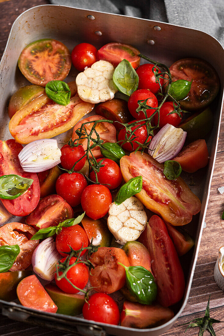 Frische Tomaten, Knoblauch, Schalotten, Basilikum in einer Auflaufform