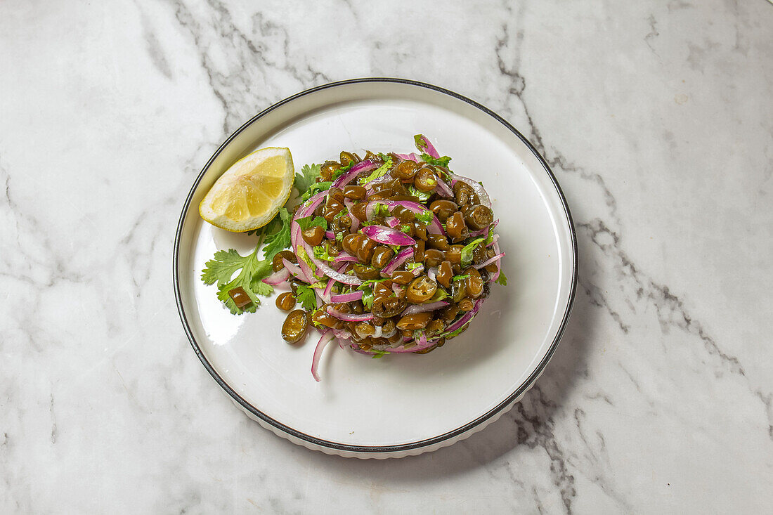 Seetang-Salat. Chilenische Cebiche de cochayuyo aus gehackten Cochayuyo-Algen mit Zitronen, Koriander, Zwiebeln und Salz, weißer Teller, Ansicht von oben