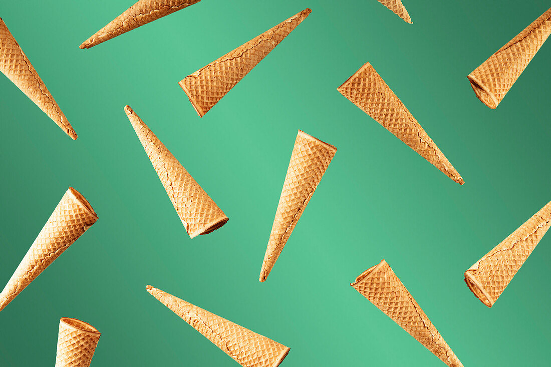 Ice cream cone pattern. Green background with colour gradient. Sweet, summer and empty concept. Ice cream in a state of suspension. Top view. Flat lay