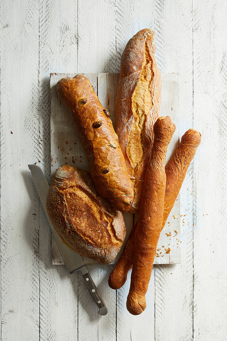 Verschiedene französische Weißbrote, Baguette, Petit Pan auf weißem Holzuntergrund