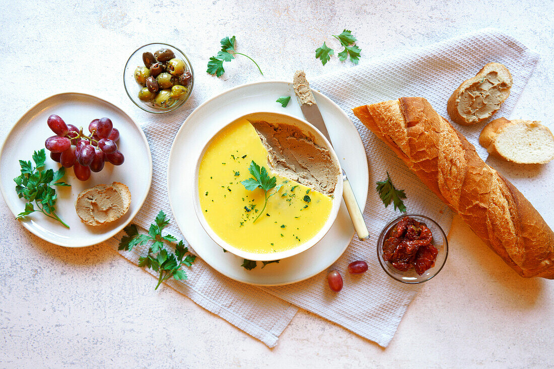 Chicken liver pâté served with crusty French baguette bread, olives and semi-dried tomatoes. Horizontal orientation.