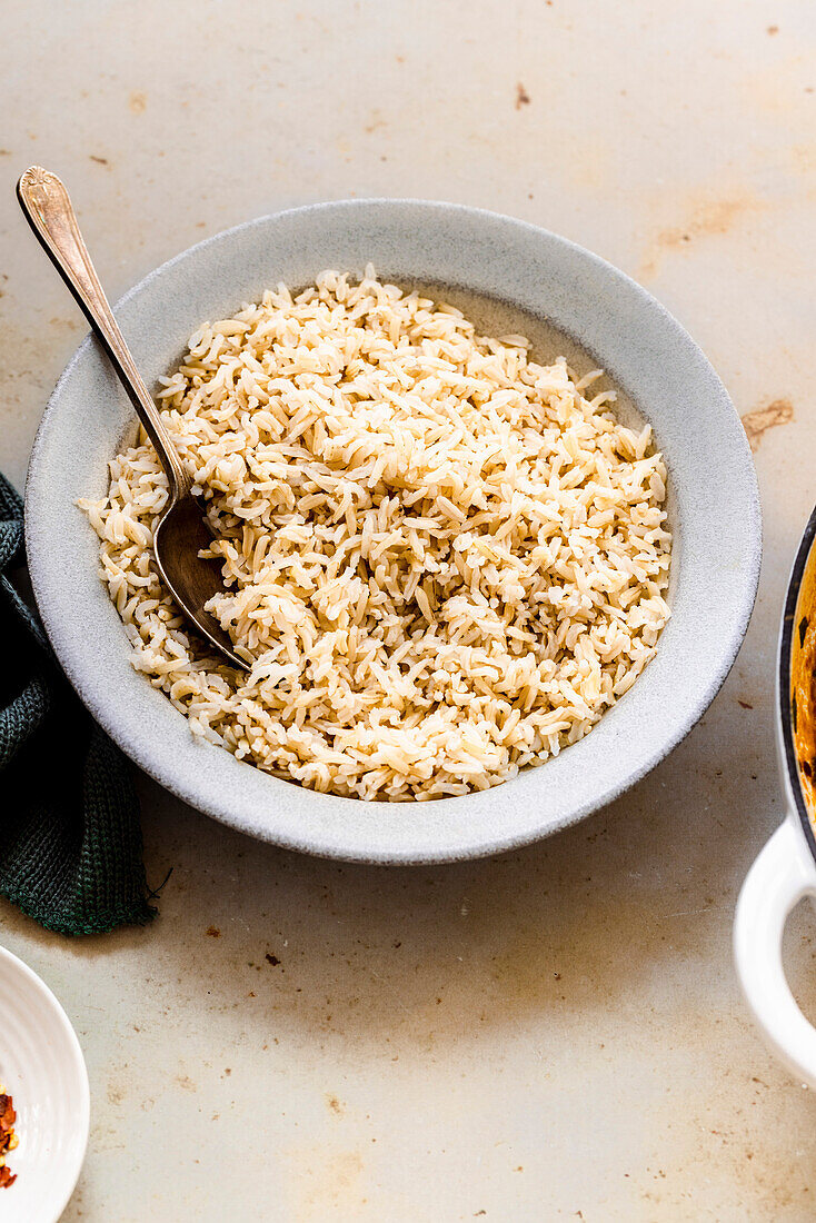 Brown basmati rice with a spoon in a white bowl