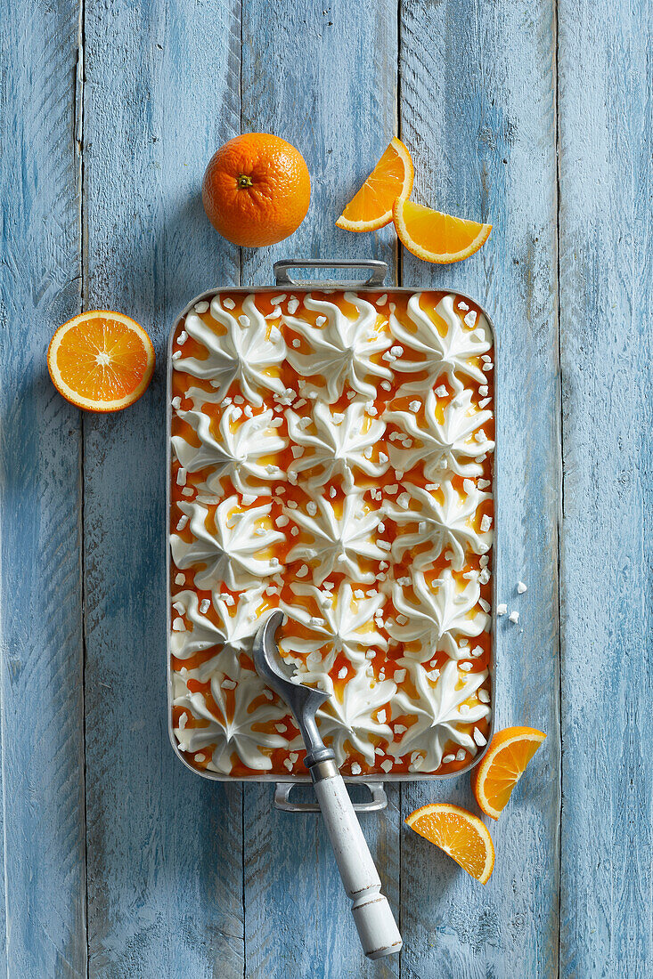 Homemade fresh vanilla-orange ice cream dessert with meringue pieces on a blue wooden background