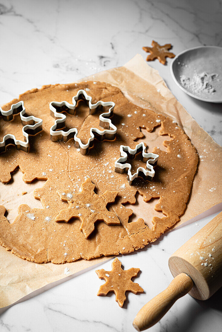 rolled out gingerbread dough with snowflake cookie cutters