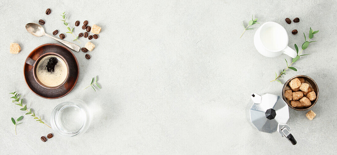 Flat lay with Moka pot, espresso cup, ground coffee, milk, sugar and coffee beans on a grey concrete background. Header with brewing coffee ingredients. Copy space