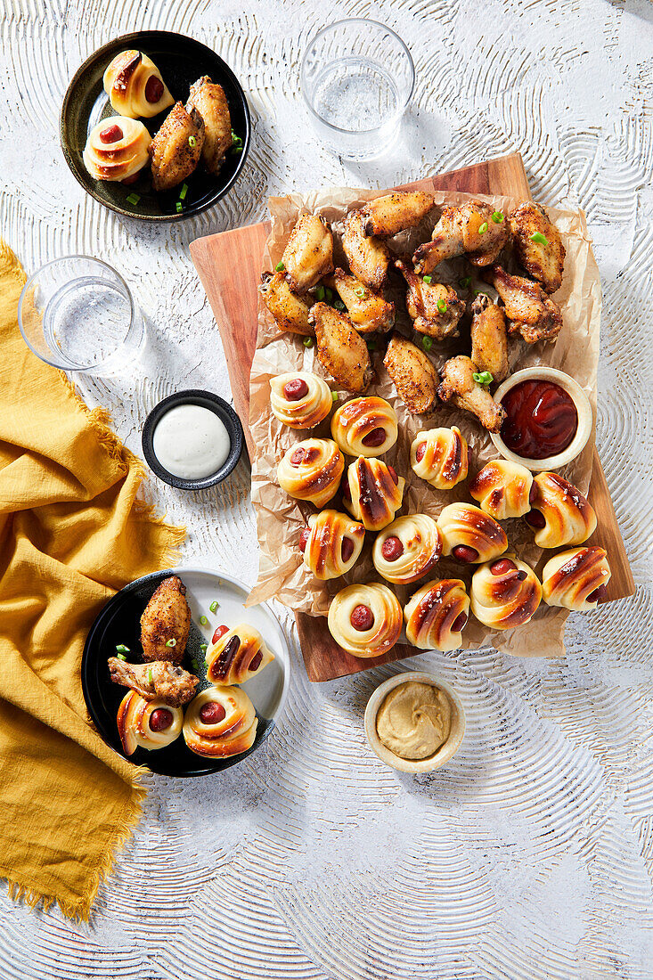 Holiday meal with chicken wings and pigs in a blanket sausages.