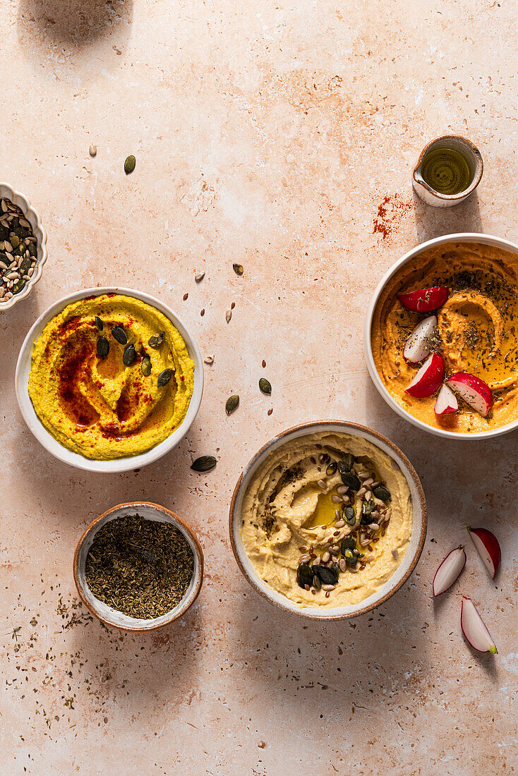 Bowls of fresh hummus with seeds, oregano and paprika