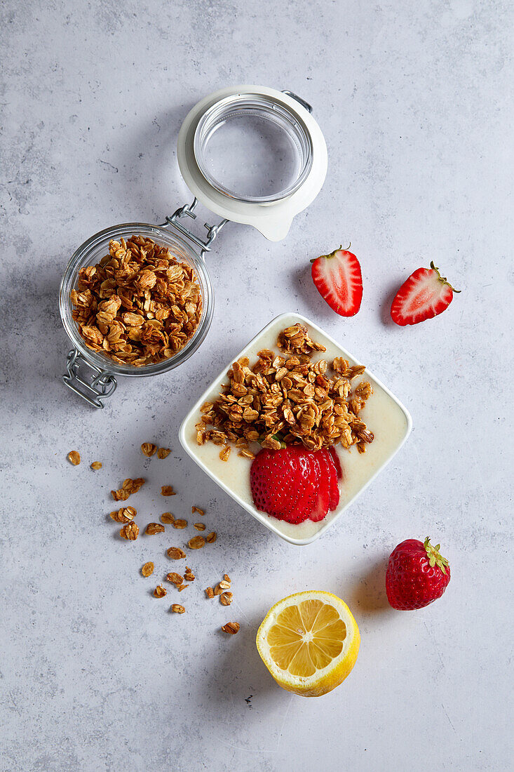 Bowl of lemon and strawberry smoothie with granola on a neutral background with soft shadows