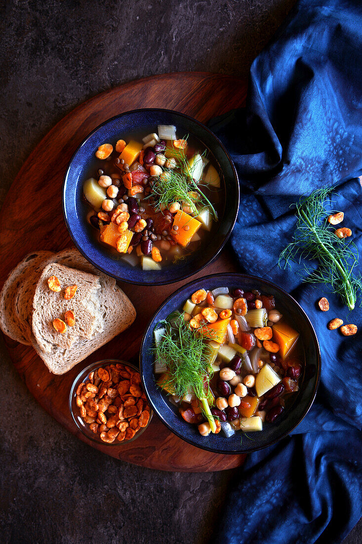 Bowls of Sardinian-style minestrone longevity soup served with sourdough bread and roasted fava beans.