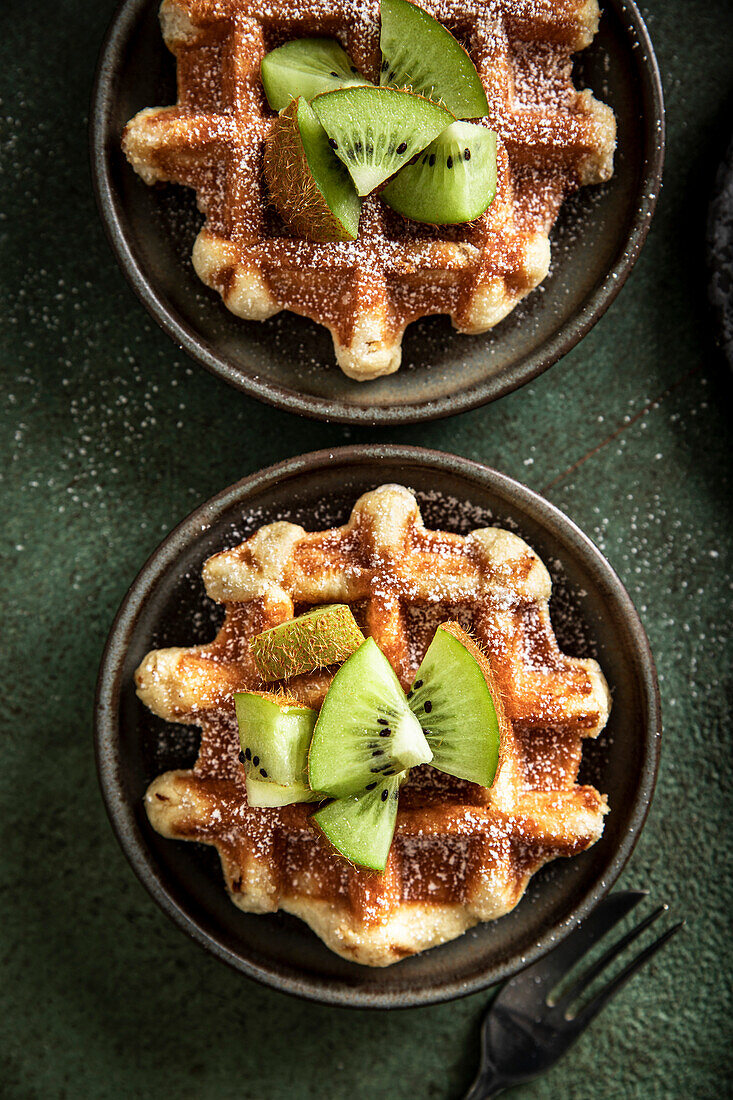 Morgenwaffeln mit Kiwi und Gabel auf einer grünen Fläche