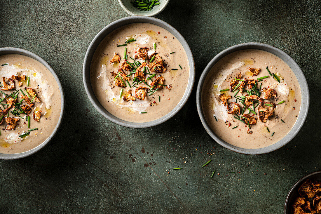 Mushroom soup bowls topped with wild mushrooms on a green surface