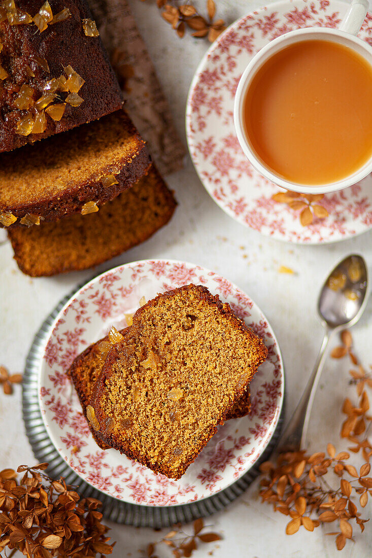 Slices of gingerbread on a plate with a cup of tea on the side.