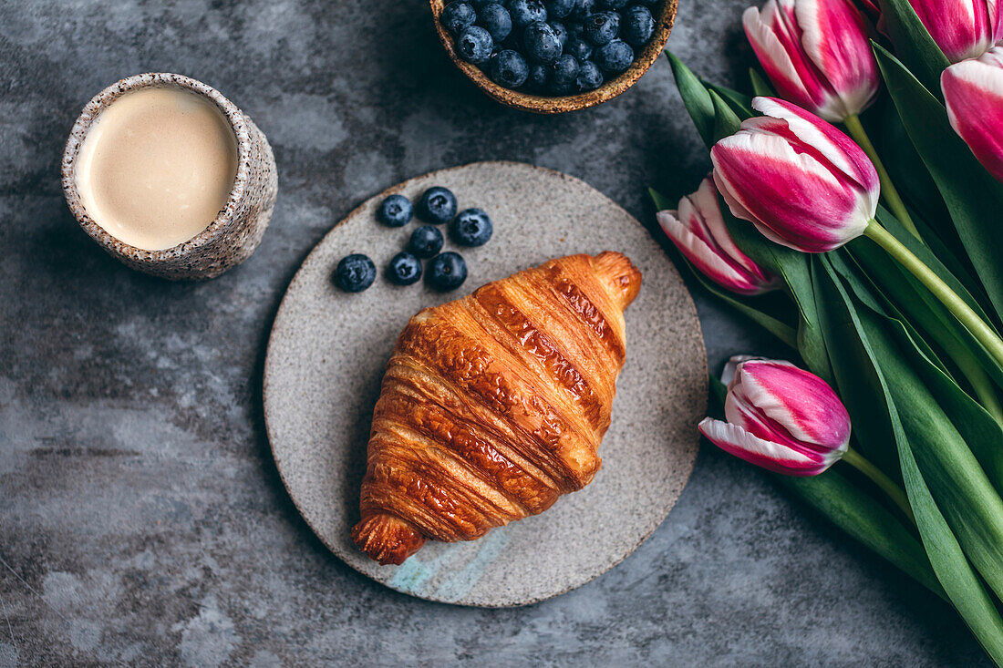 Croissant and blueberries on a ceramic plate