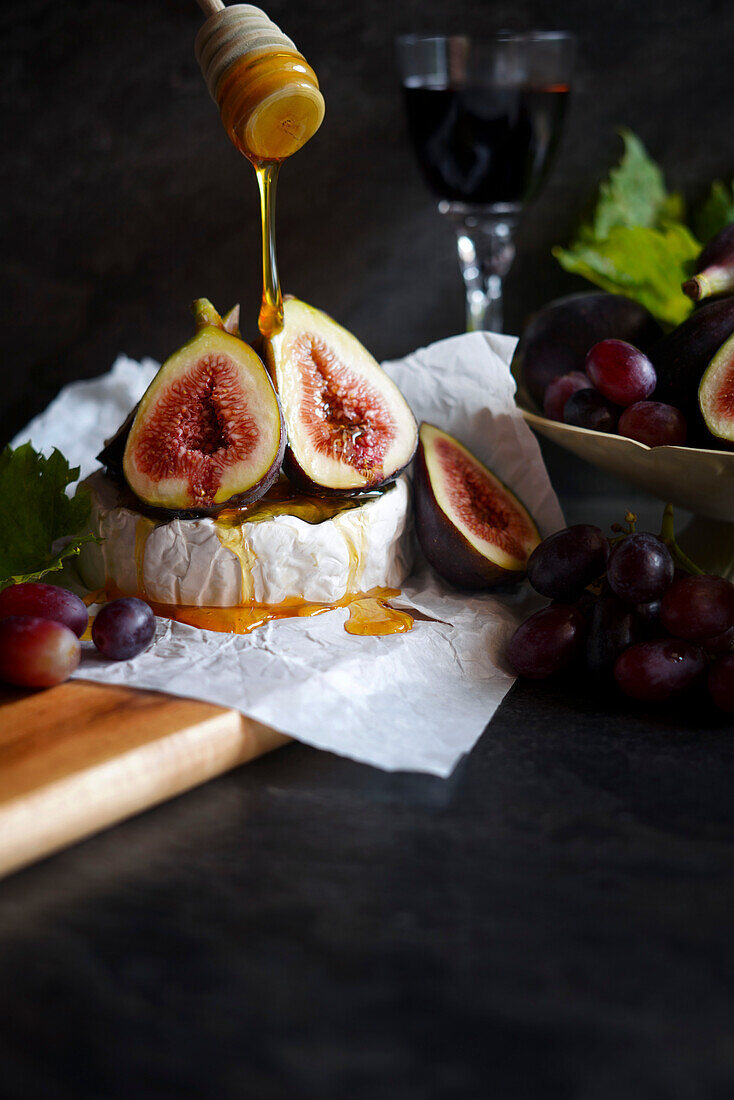 Brie cheese served with figs, honey and grapes, with negative copy space.