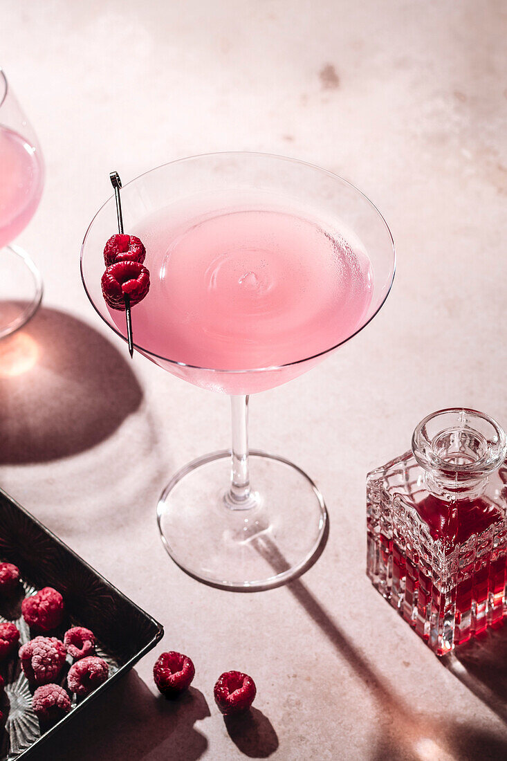 Pink cocktail with raspberries on a pink surface