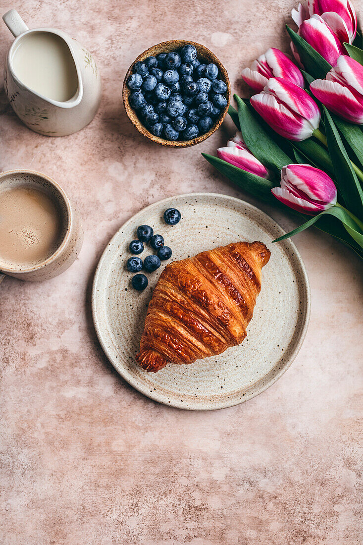 Croissant und Blaubeeren auf einem Keramikteller