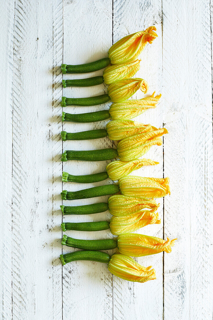 Fresh home-grown zucchini flowers on a white wooden background