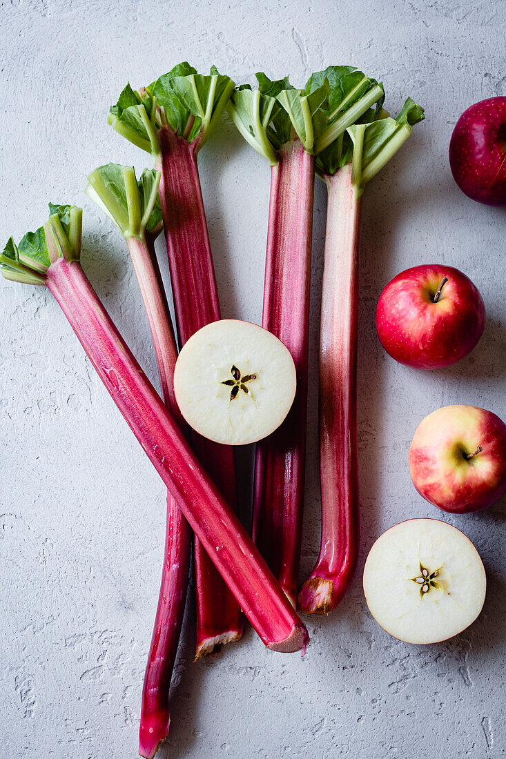 Apples and rhubarb stalks on a grey background