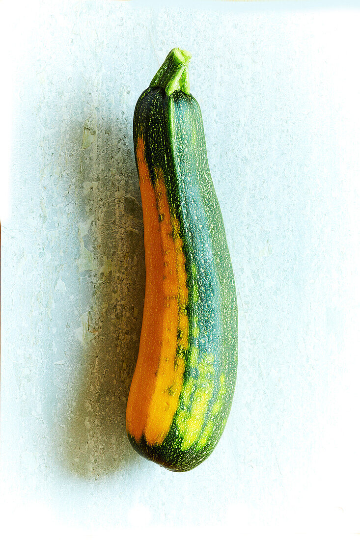 Fresh home-grown yellow-green zucchini on a light green stone background