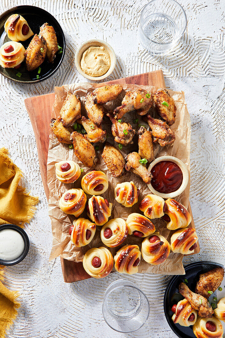 Game Day Food Spread mit Hähnchenflügeln und Würstchen im Schlafrock