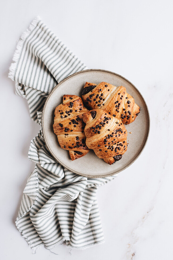 Schokoladencroissants auf Teller und weißem Hintergrund