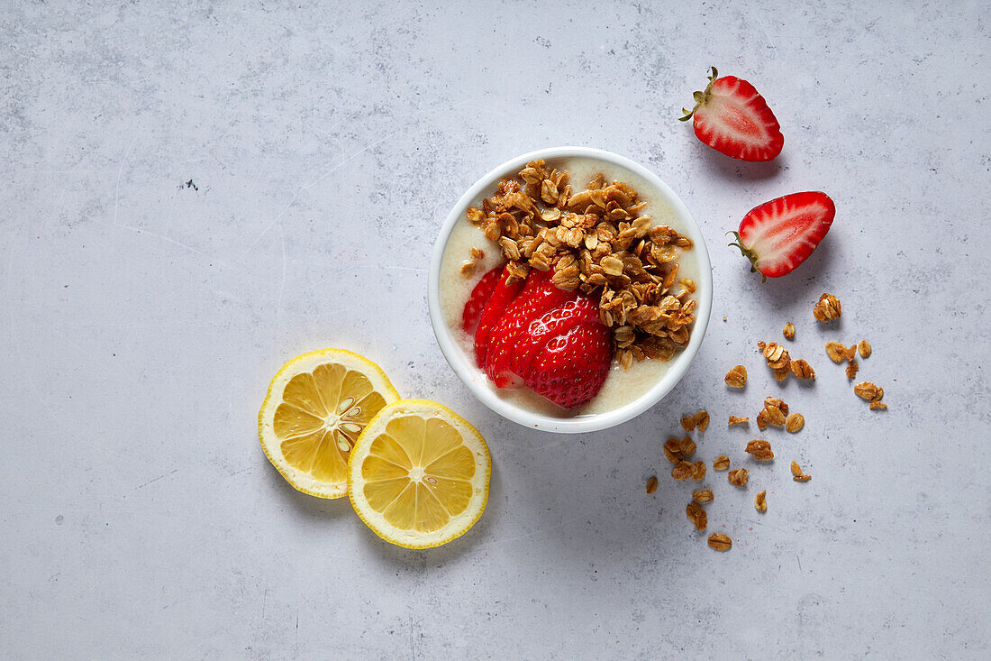 Zitronen-Erdbeer-Smoothie-Schale mit Müsli auf neutralem Hintergrund mit weichen Schattierungen