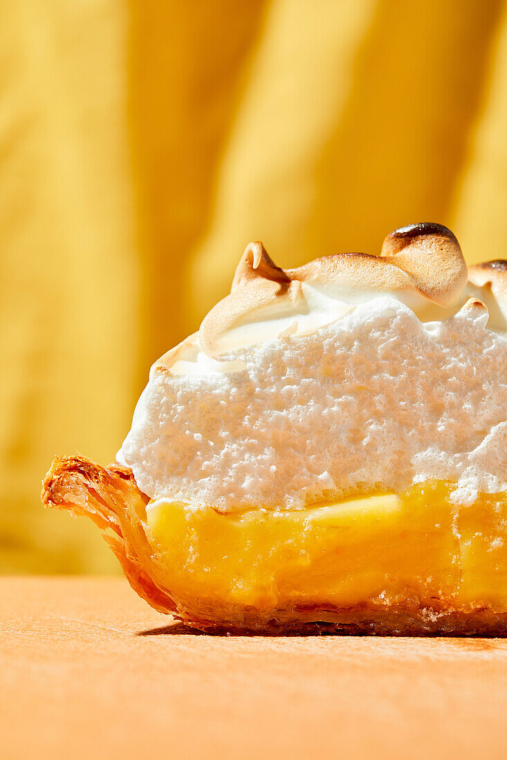 Lemon meringue pie with bright hard light on orange foreground and yellow background