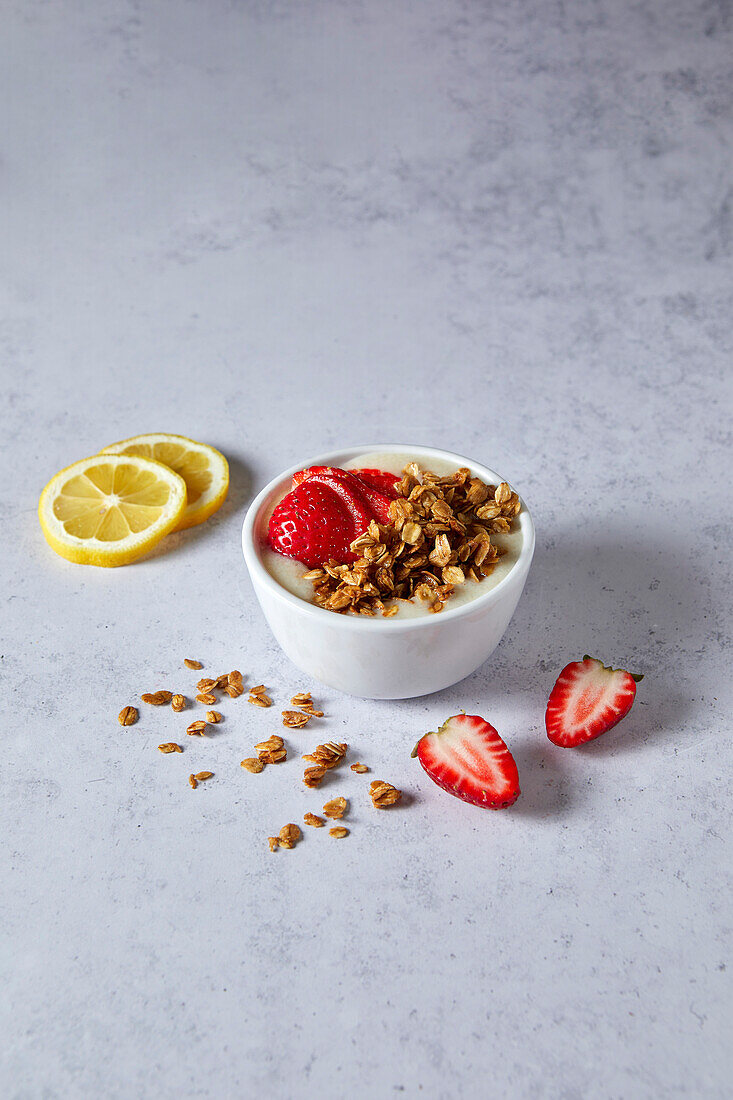 Lemon Strawberry Smoothie Bowl with Granola on a Neutral Background with Soft Shadows