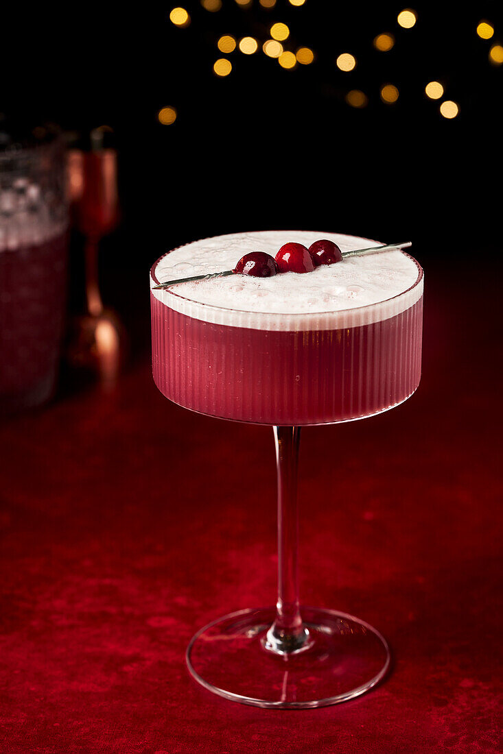 Glühwein sauer mit Preiselbeeren auf roter Fläche mit Lichterketten und Gläsern