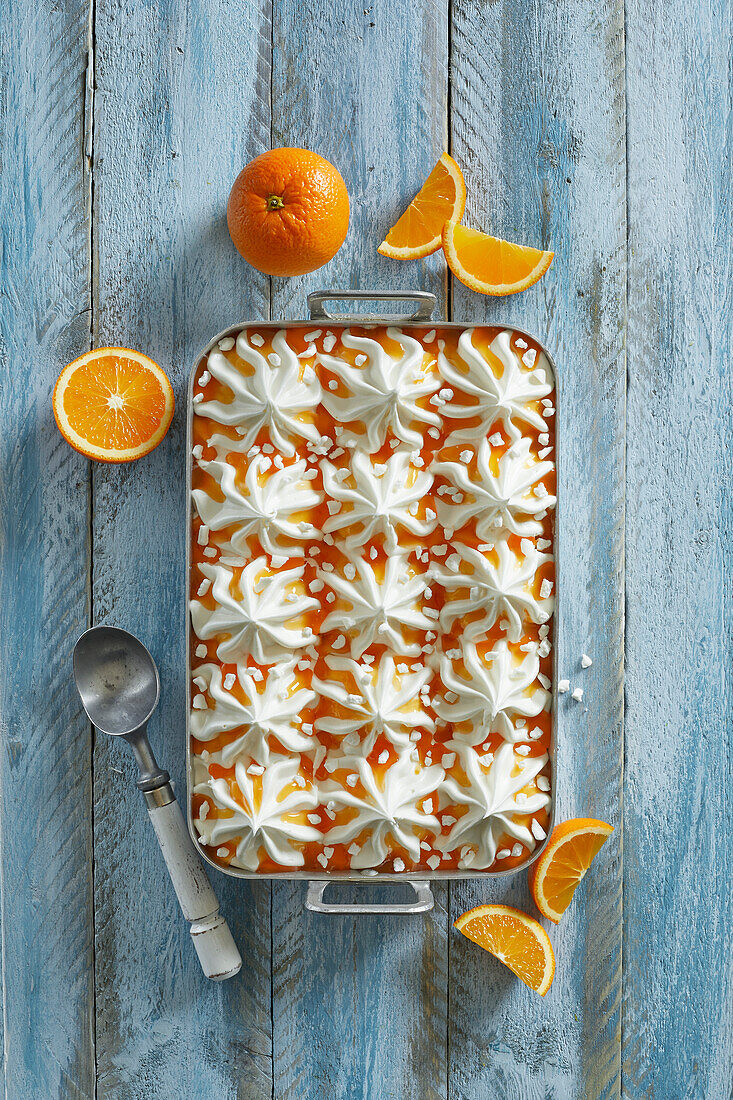 Homemade fresh vanilla-orange ice cream dessert with meringue pieces on a blue wooden background