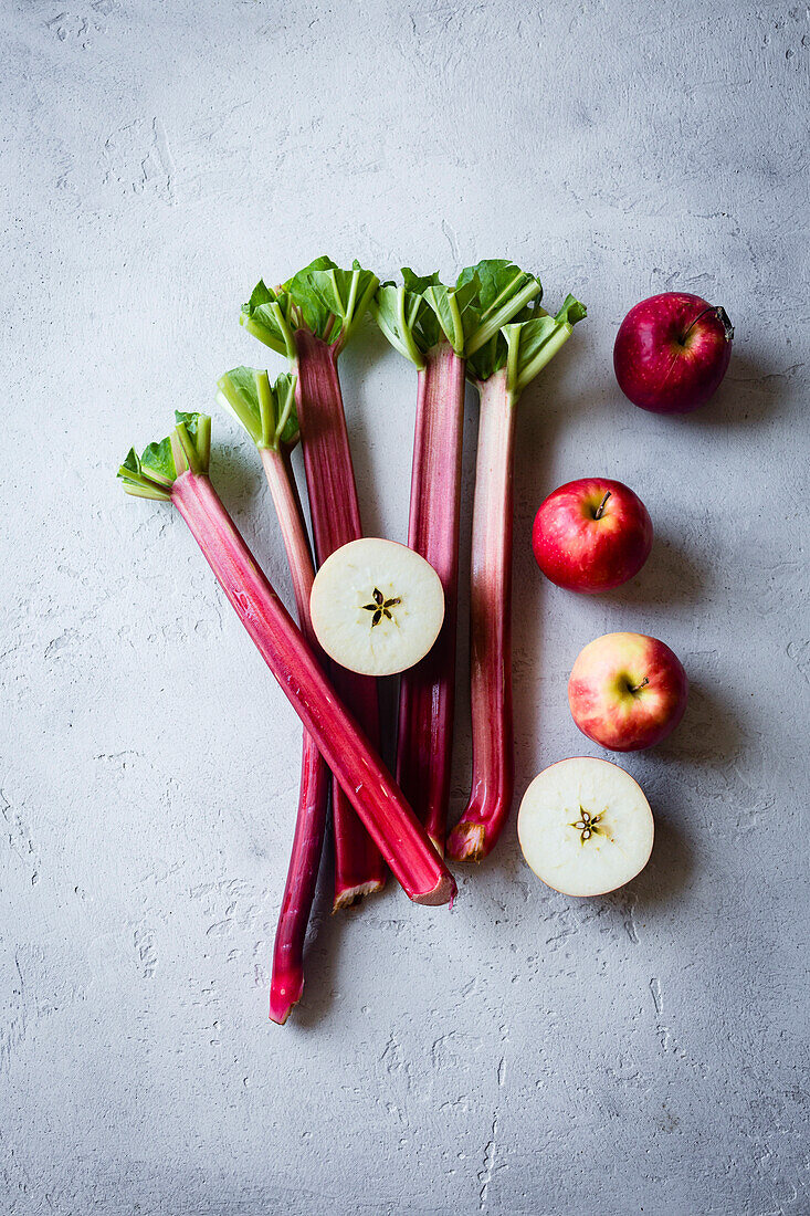 Apples and rhubarb stems on a grey background