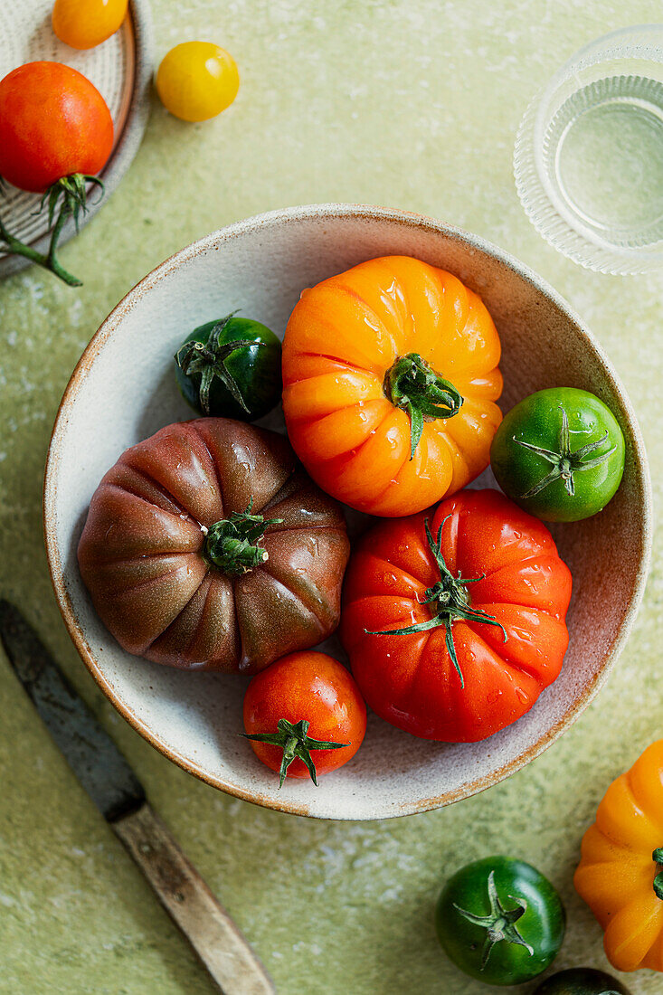 Fresh, colourful heritage tomatoes on a green background