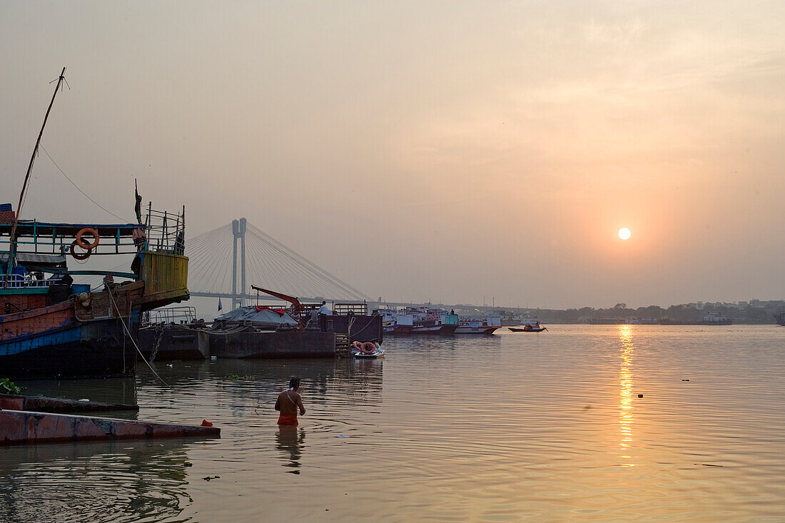 Bather and sunset over the Hooghly River with the Vidyesagar Setu Bridge in the background, Kolkata (Calcutta), West Bengal, India, Asia