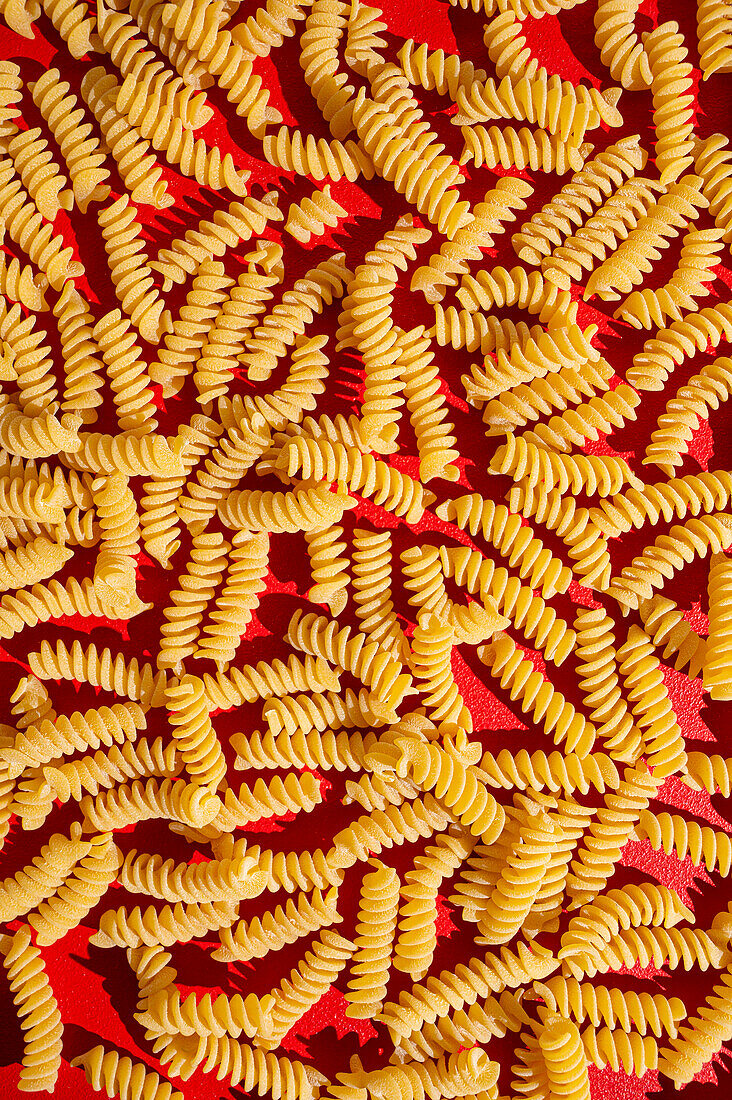 Fusili Pasta Nahaufnahme auf rotem Hintergrund