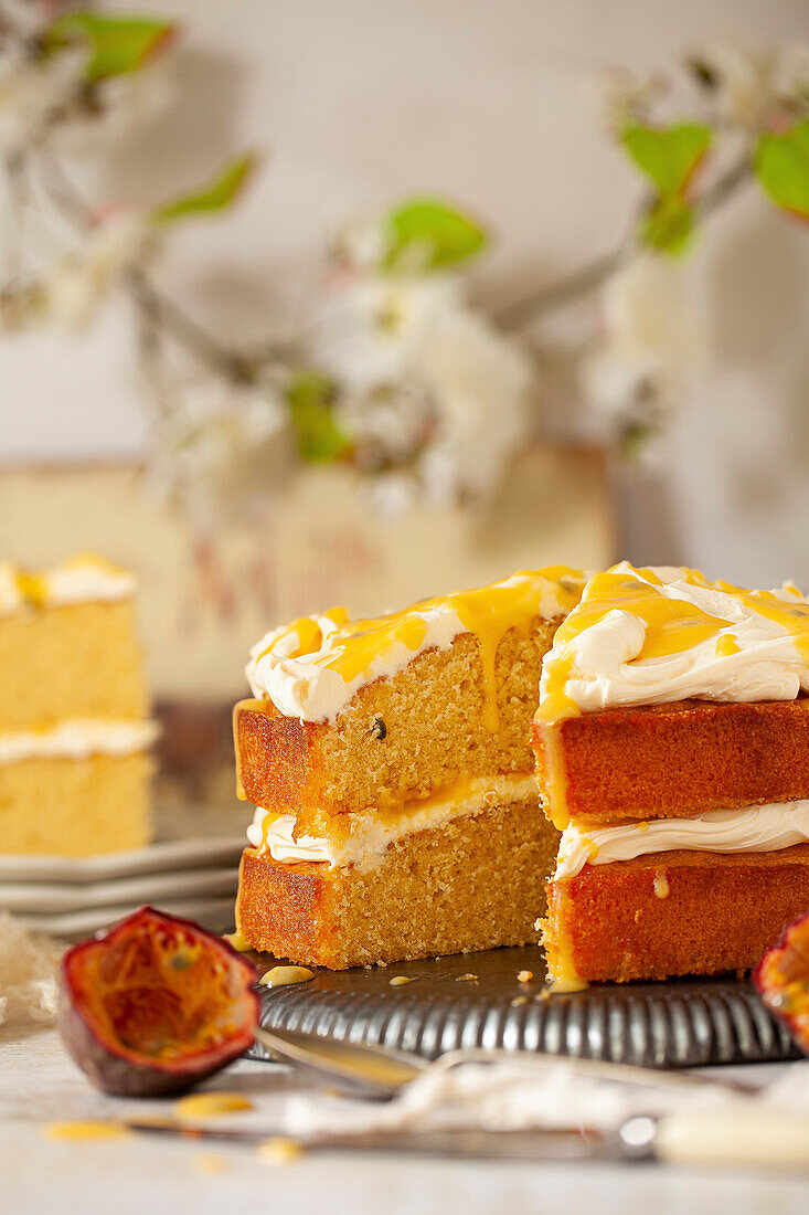 A passionfruit sponge cake with a slice removed. Filled with mascarpone cream frosting, passionfruit curd and passionfruit coulis.