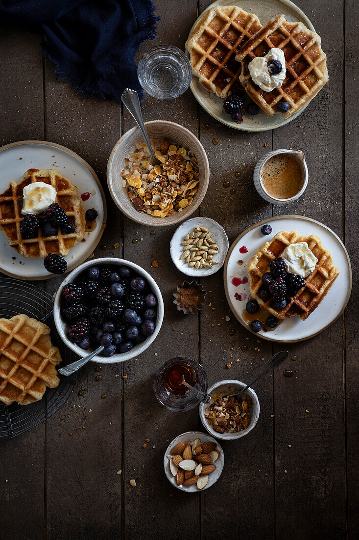 Top view of a bowl of breakfast cereals, Belgian waffles with berries and cream on a wooden table.