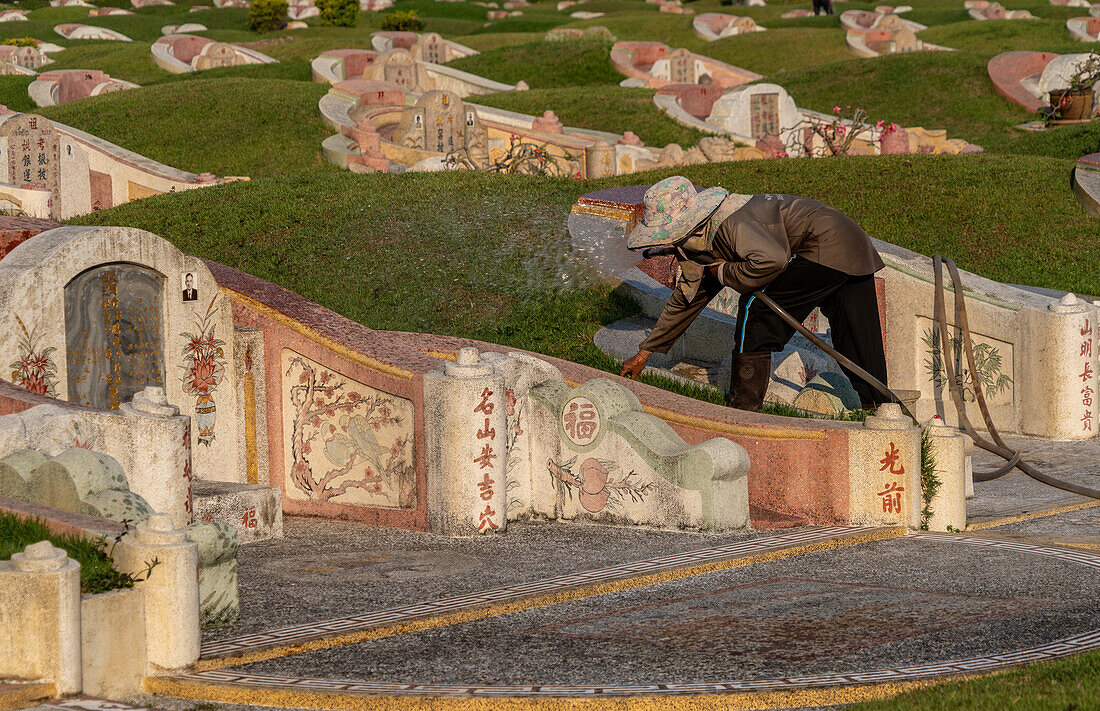 Worker looking after tombstones at Chinese cemetery, Chiang Mai ,Thailand, Southeast Asia, Asia