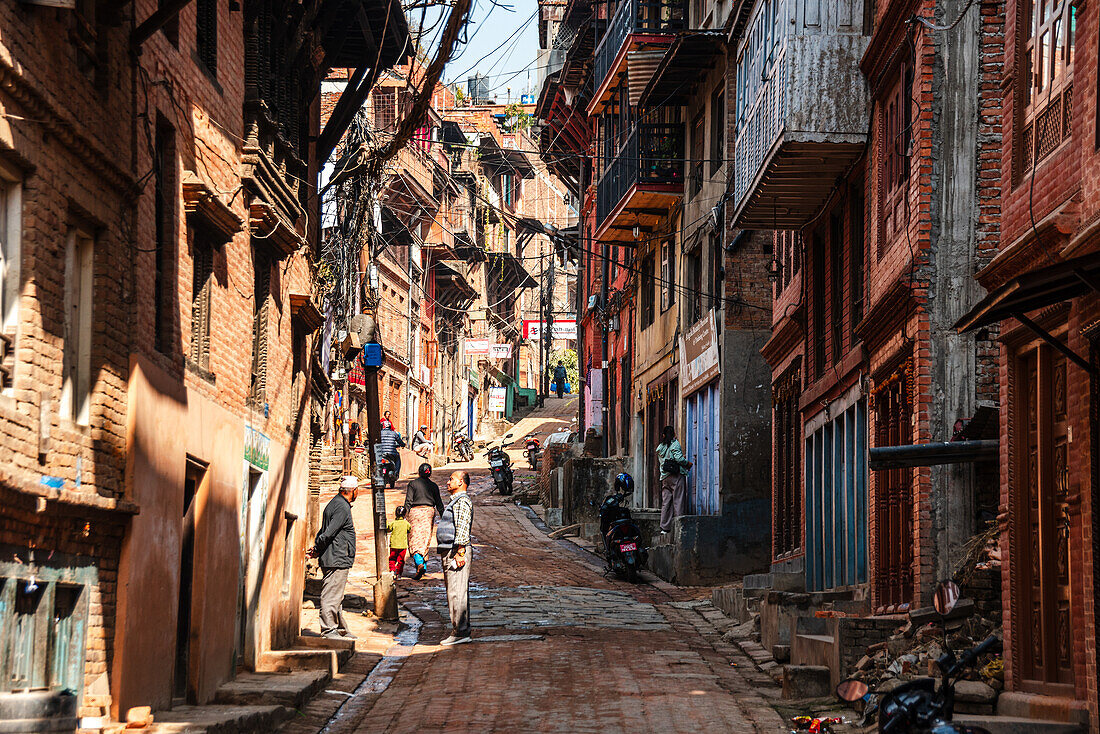 Blick entlang einer engen Gasse mit traditionellen Backsteinhäusern im Zentrum von Bhaktapur, Kathmandu, Nepal, Asien