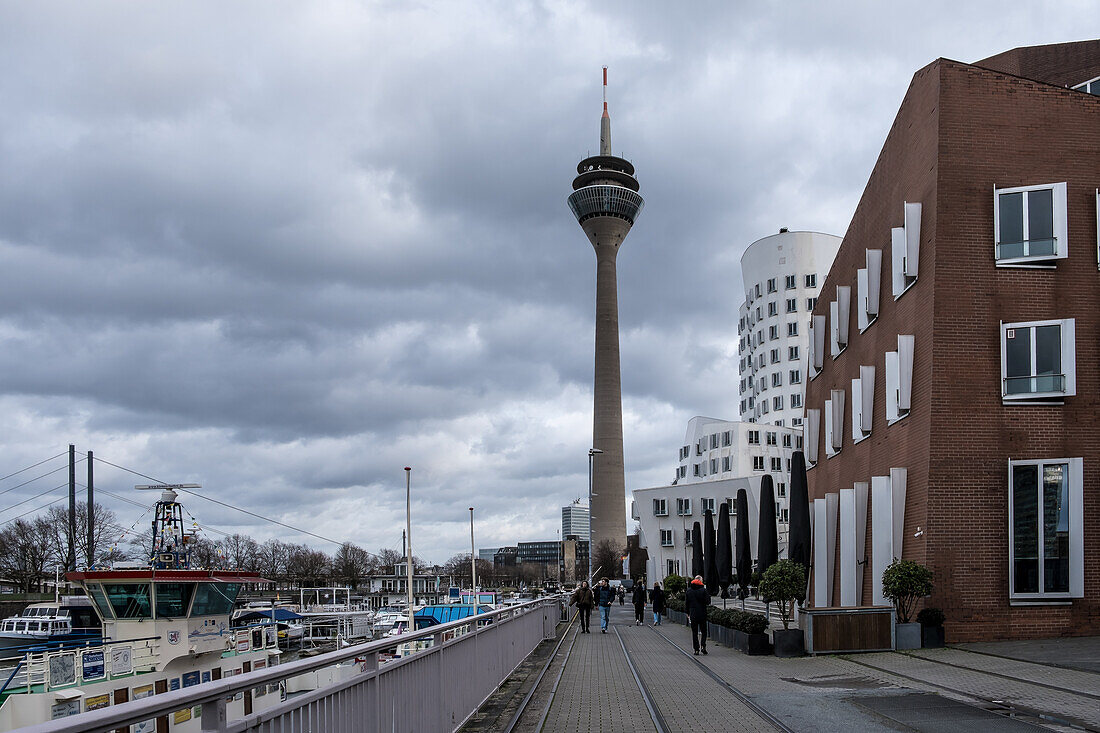 Blick auf den Neuen Zollhof, benannt nach einer ehemaligen Zollanlage, ein markantes Wahrzeichen des Düsseldorfer Hafens, Teil des neu gestalteten Düsseldorfer Hafens, mit dem Rheinturm im Hintergrund, Düsseldorf, Nordrhein-Westfalen, Deutschland, Europa