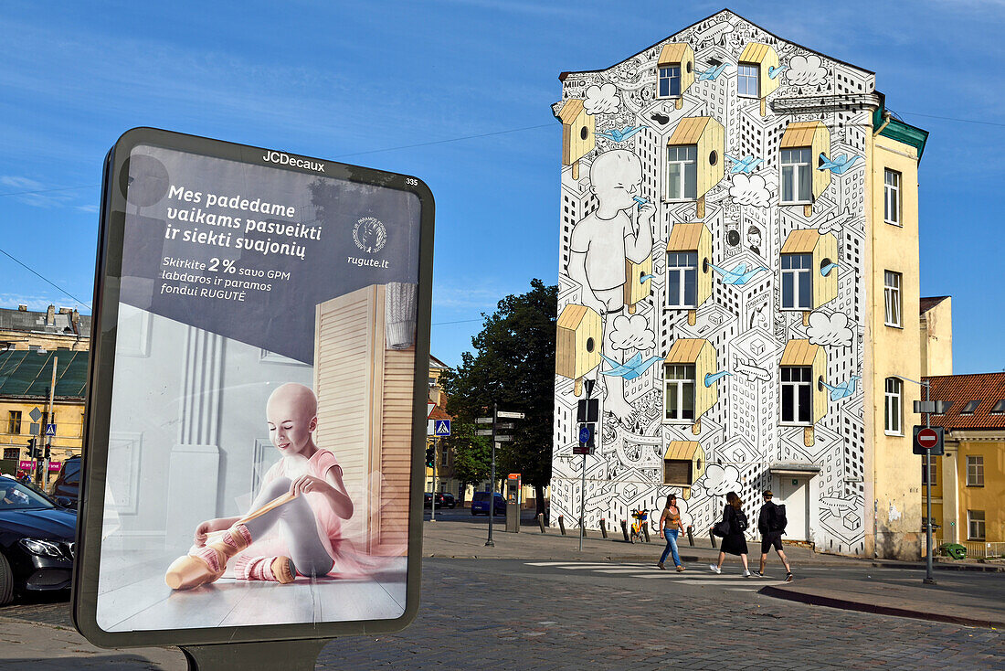 Billboard with poster calling for a donation for RUGUTE childhood cancer fund, in front of a mural painting by the Italian artist Millo, on the building opposite Hales Market, Pylimo Street 56, Vilnius, Lithuania, Europe