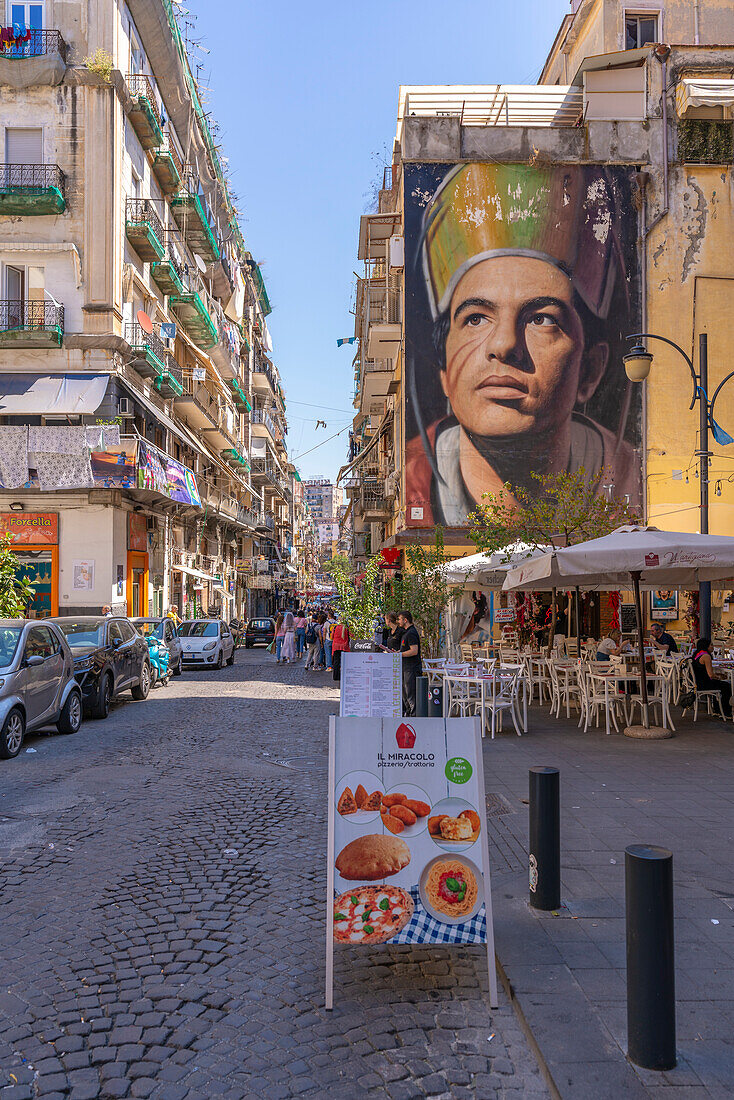 Blick auf Cafés und San Gennaro di Jorit Agoch in der belebten Via Forcella, Neapel, Kampanien, Italien, Europa