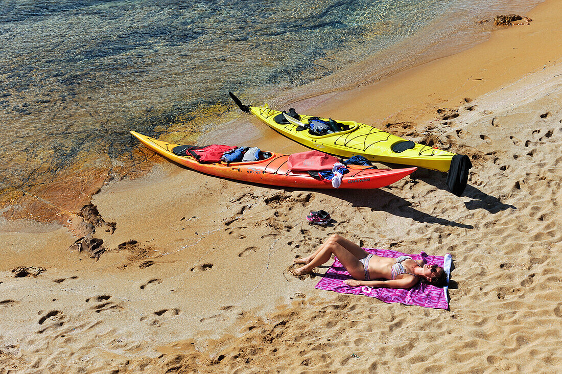 Kajakfahrer ruht sich am Strand einer kleinen Insel in der Bucht Cala Pregonda in der Nähe von Kap Cavalleria an der Nordküste von Menorca, Balearen, Spanien, Mittelmeer, Europa aus