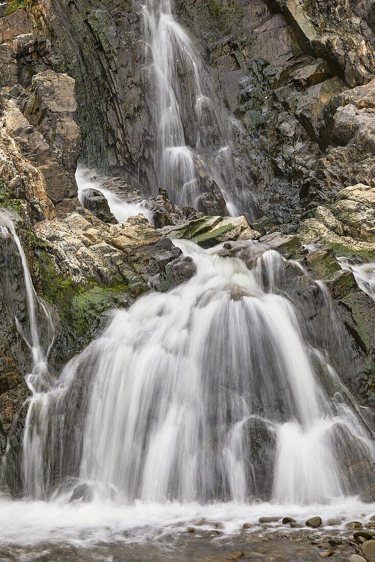 Wasserfall, der sich über eine felsige Klippe ergießt, mit unscharfer Bewegung, resultierend aus einer langsamen Verschlusszeit; am Welcombe Mouth, Hartland, Nord-Devon, England, Vereinigtes Königreich, Europa