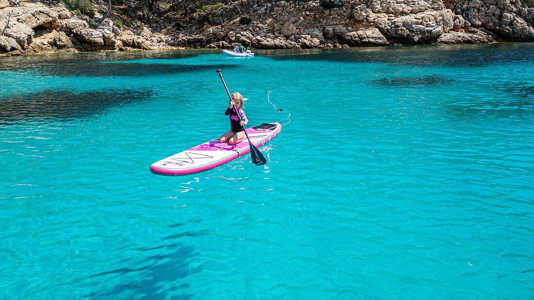 Aerial of a young girl paddling on a SUP on the Formentor Peninsula, Mallorca, Balearic islands, Spain, Mediterranean, Europe