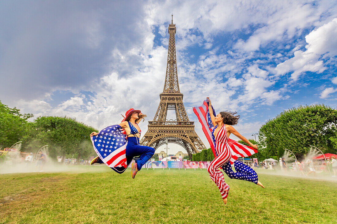 Patriotische amerikanische Frau springt und jubelt für das Team USA und die Olympischen Spiele Paris 2024 vor dem Eiffelturm, Paris, Frankreich, Europa