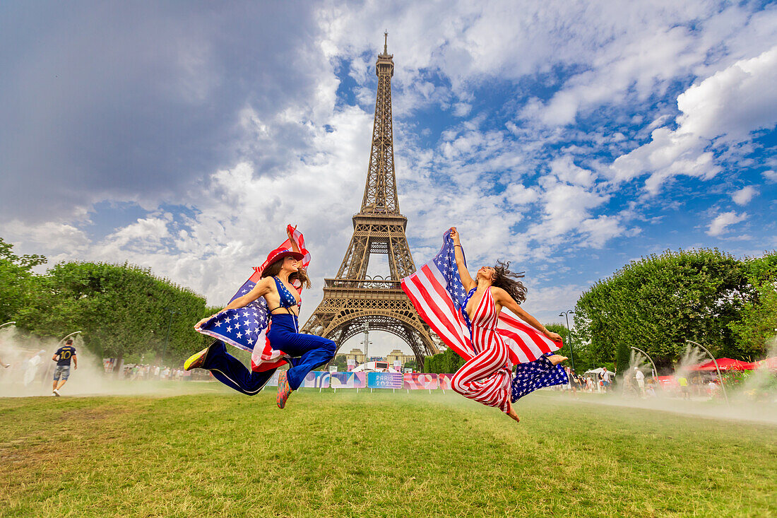 Patriotische amerikanische Frau springt und jubelt für das Team USA und die Olympischen Spiele Paris 2024 vor dem Eiffelturm, Paris, Frankreich, Europa