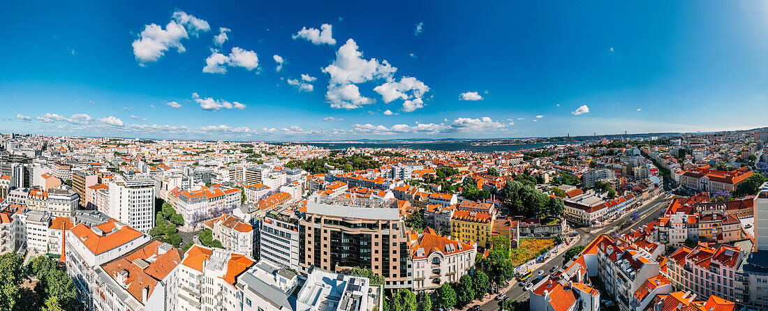 Aerial drone panoramic view of Lisbon's Baixa district on a sunny day looking south towards the Tagus with the 25 April Bridge visible, Lisbon, Portugal, Europe