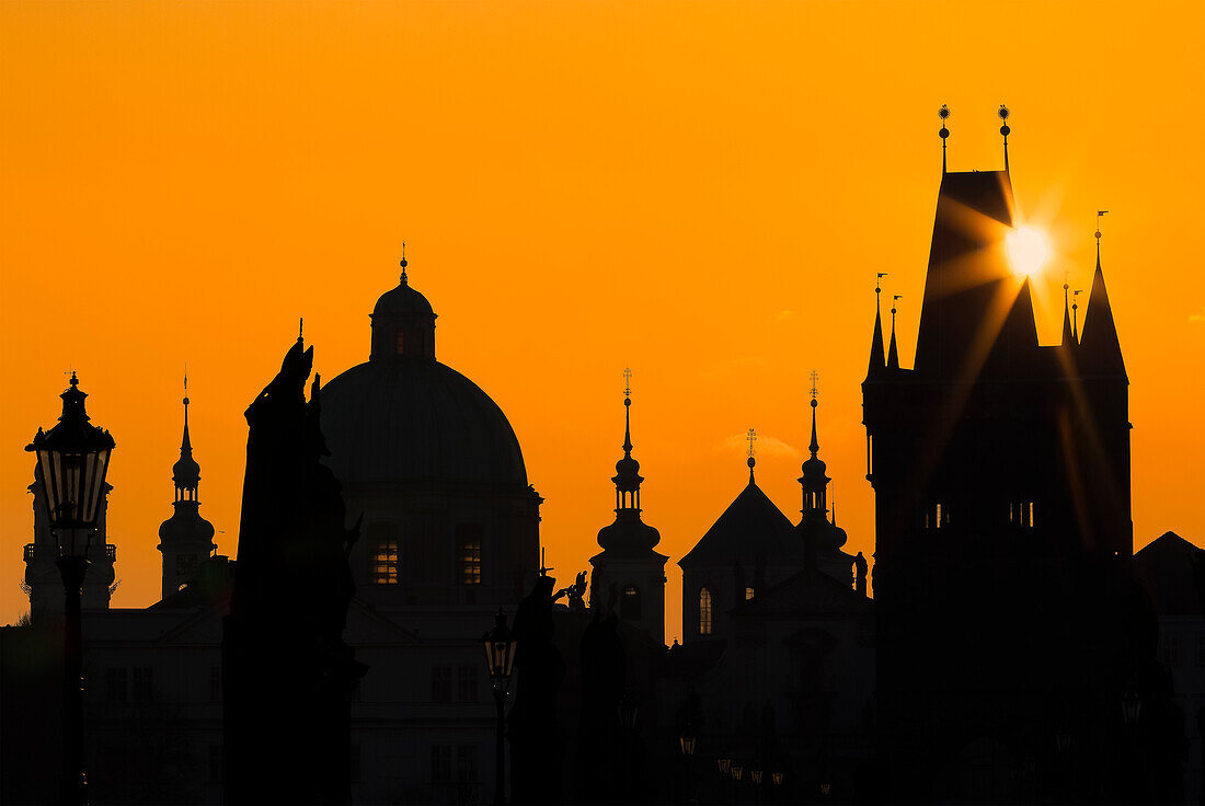 Sun rising above silhouettes of towers and spires at Charles Bridge at sunrise, UNESCO World Heritage Site, Prague, Czechia, Europe